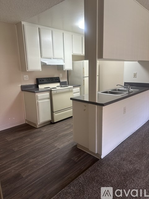 A kitchen with white cabinets and a black countertop.