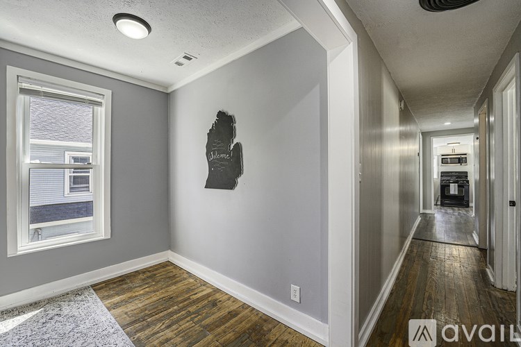 A hallway with a wooden floor and a wall hanging.