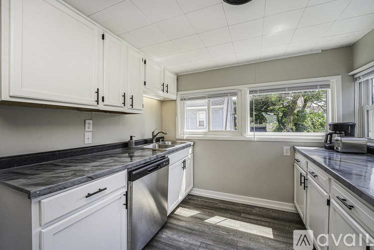 A kitchen with white cabinets and a black countertop.