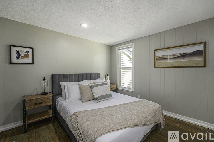A bedroom with a bed, nightstand, and two pictures on the wall.
