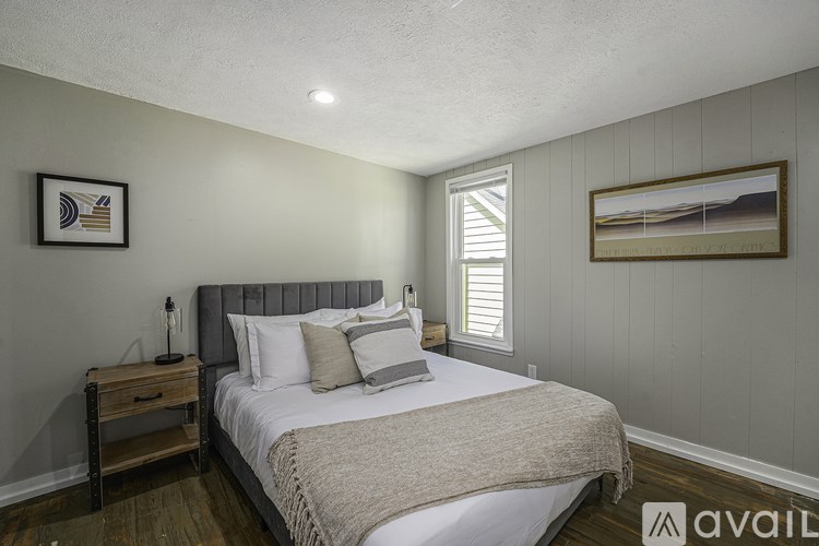 A bedroom with a bed, nightstand, and two pictures on the wall.