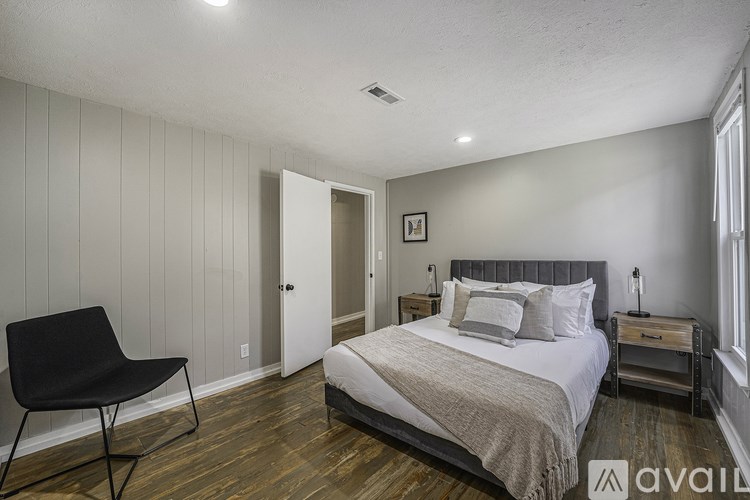 A bedroom with a bed, chair, and nightstand.