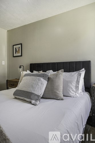 A bed with a white comforter and pillows in a room.