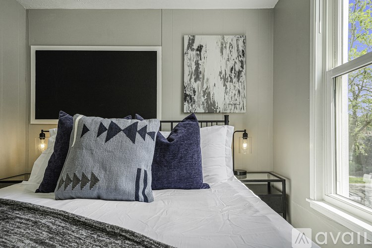 A bedroom with a bed, pillows, and a painting on the wall.