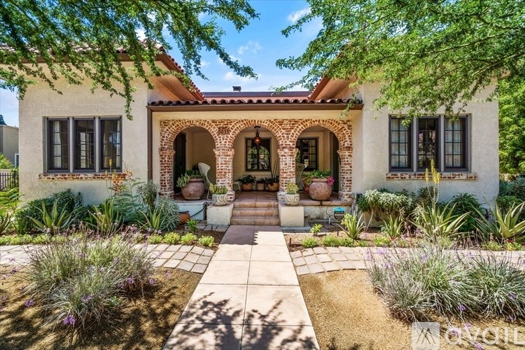 A house with a red tile roof and a white wall with a garden in front.