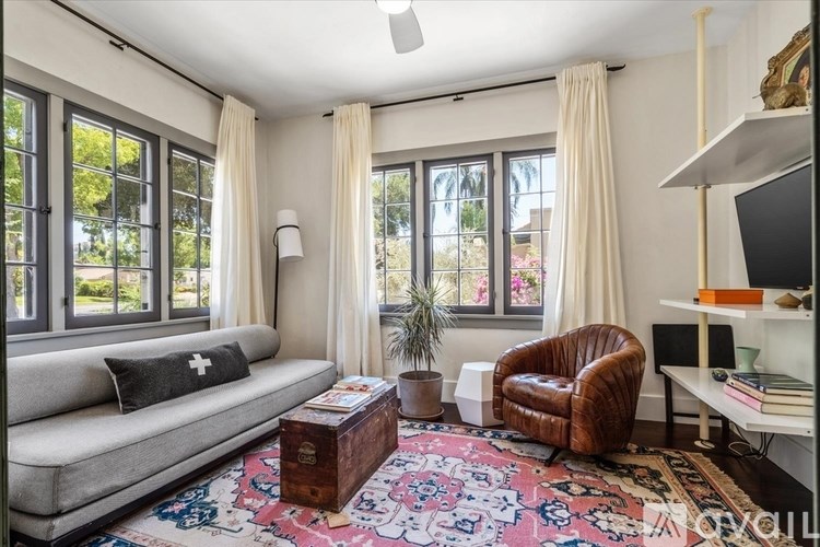 A living room with a grey sofa, a brown leather chair, a rug, and a television.