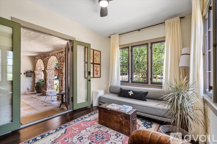 A living room with a sofa, a rug, and a plant.