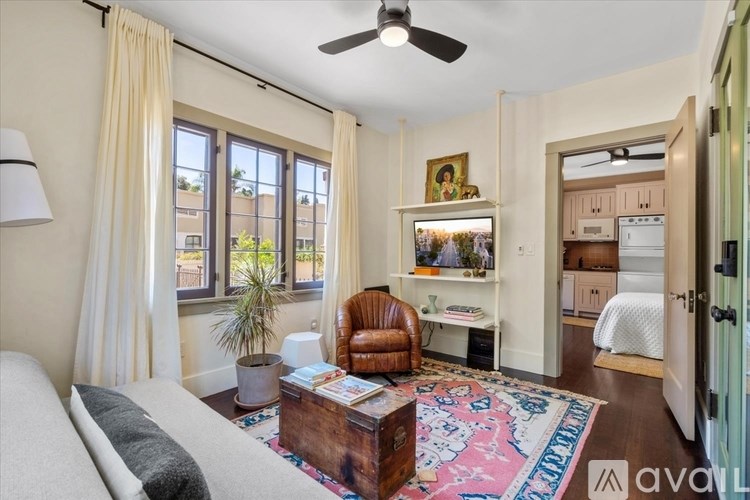 A living room with a white couch, a brown leather chair, a wooden coffee table, and a ceiling fan.