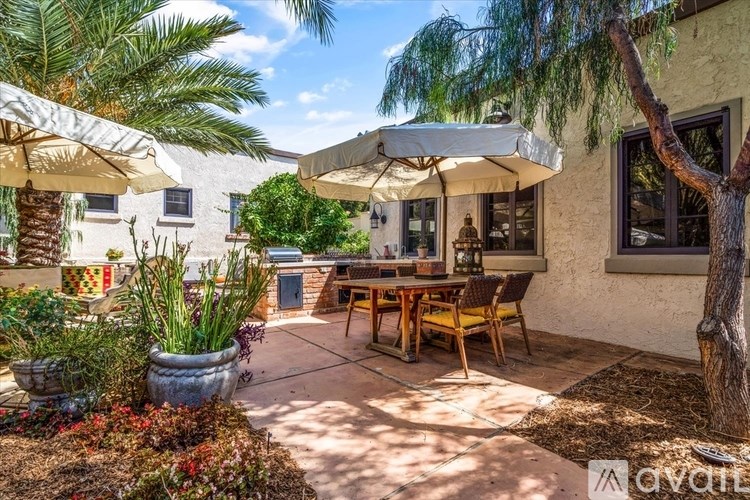 A patio with a table and chairs under umbrellas.