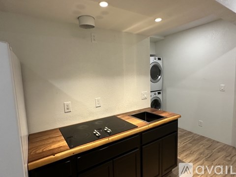 A kitchen with a wooden counter top and a washing machine in the background.