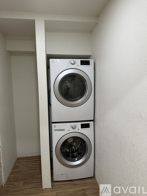 A stacked washer and dryer in a small room.