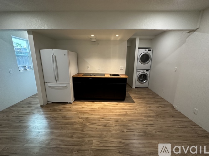 A kitchen with a white fridge, black countertop, and a washer and dryer in the corner.