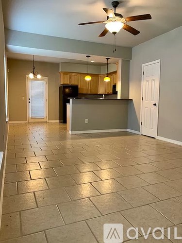 A spacious room with a ceiling fan and tiled flooring.
