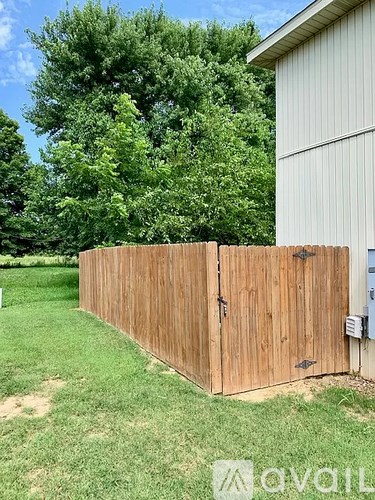 A wooden fence in front of a green lawn and a white building.