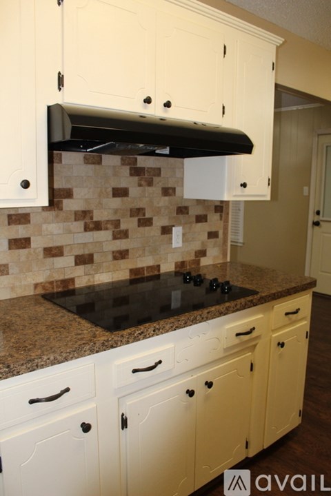 A kitchen with white cabinets and a black stove top.
