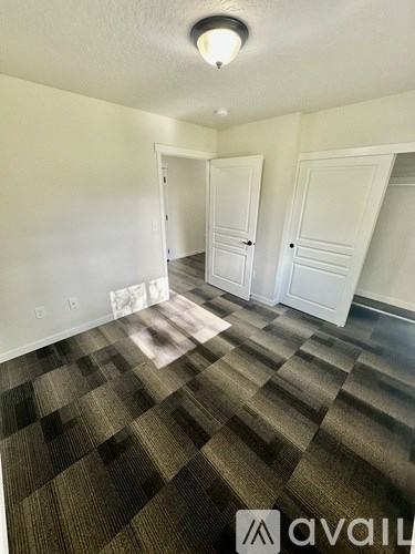 A room with carpeted floor and two doors.
