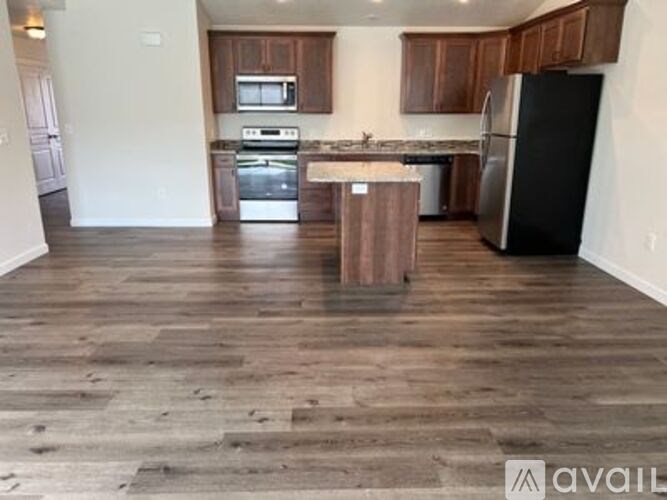 A kitchen with wooden floors and a black refrigerator.