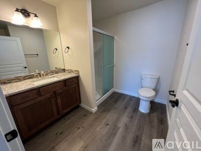 A bathroom with a toilet, sink, and mirror.