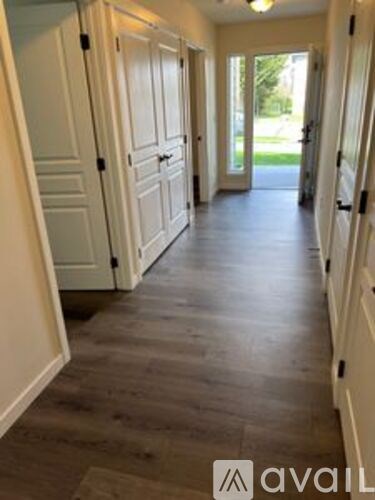 A hallway with white doors and a wooden floor.