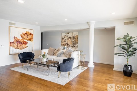 A living room with a black chair, a white couch, and a painting on the wall.