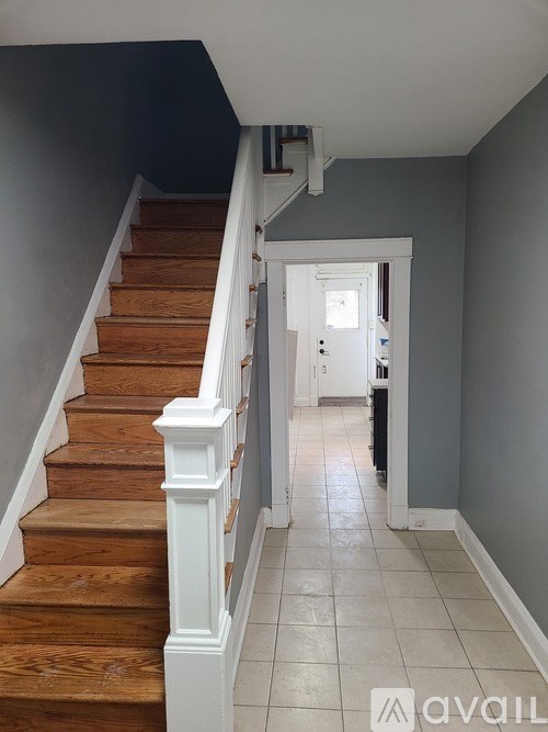 A staircase with wooden steps and white railings leads to a doorway.