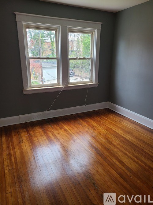 A room with wooden floors and a window showing a view of a street.