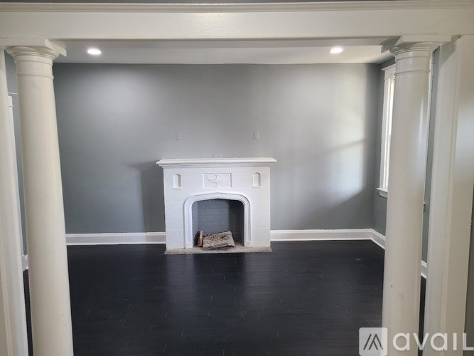 A white fireplace in a room with grey walls and black flooring.