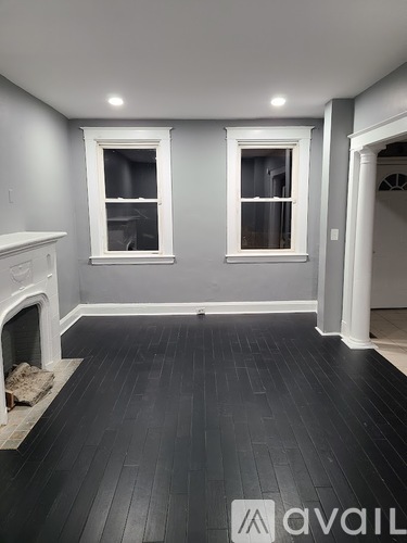 A room with a fireplace and two windows.