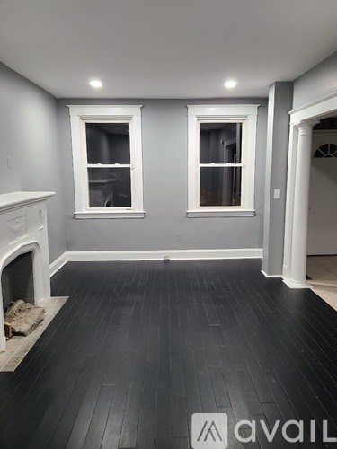 A room with a fireplace and two windows.