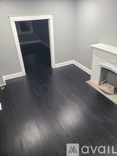 A room with a fireplace and a doorway leading to another room.