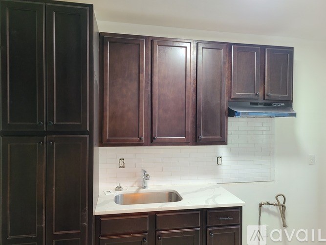 A kitchen with dark brown cabinets and a white countertop.