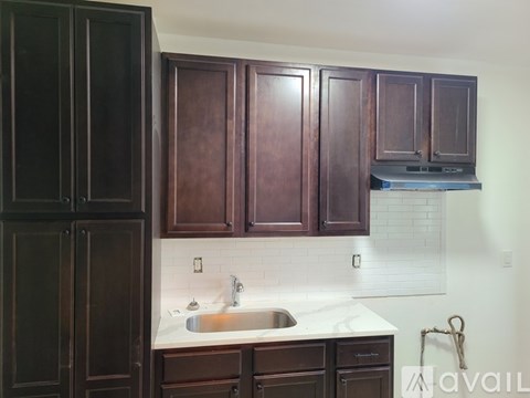 A kitchen with dark brown cabinets and a white countertop.