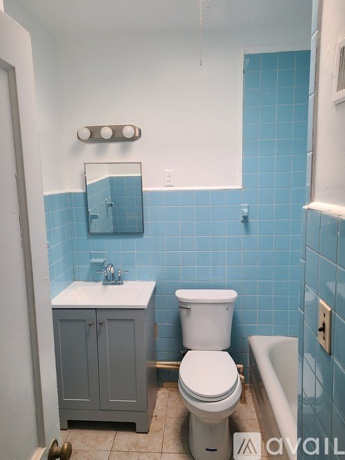 A white toilet sits in a blue tiled bathroom.