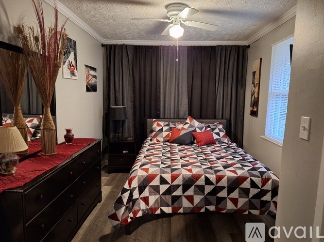 A bedroom with a bed, dresser, and ceiling fan.