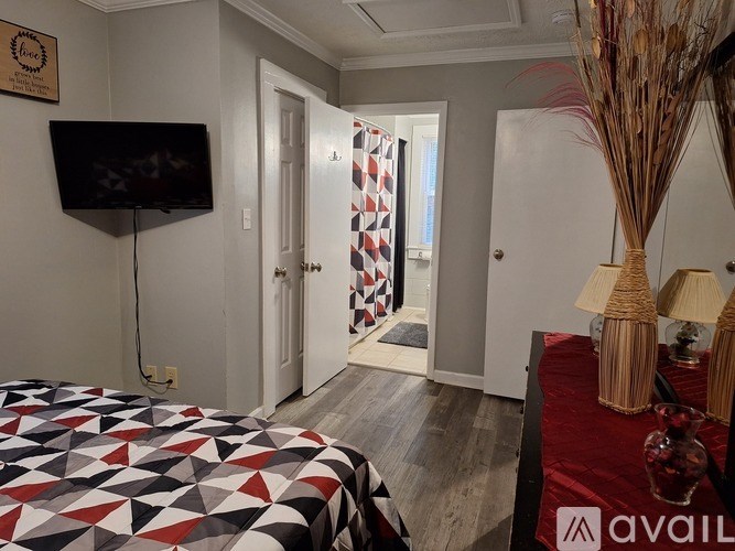 A bedroom with a bed, a television, and a vase on a table.