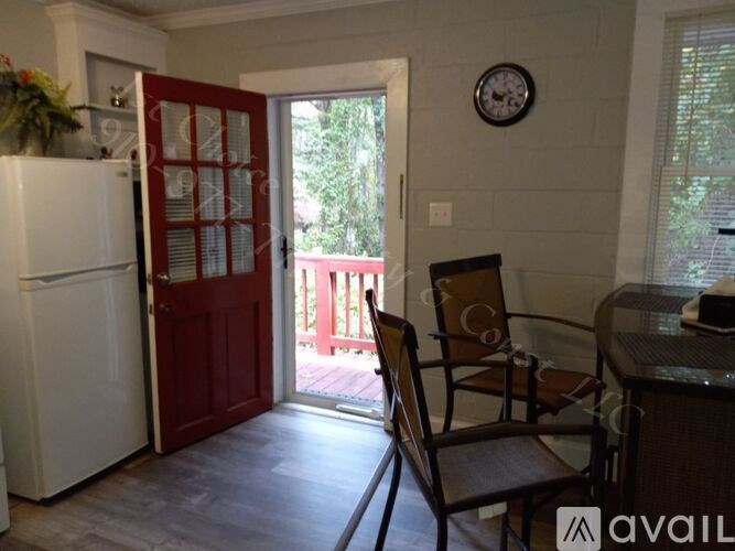 A kitchen with a white fridge, a red door, a brown chair and a table.