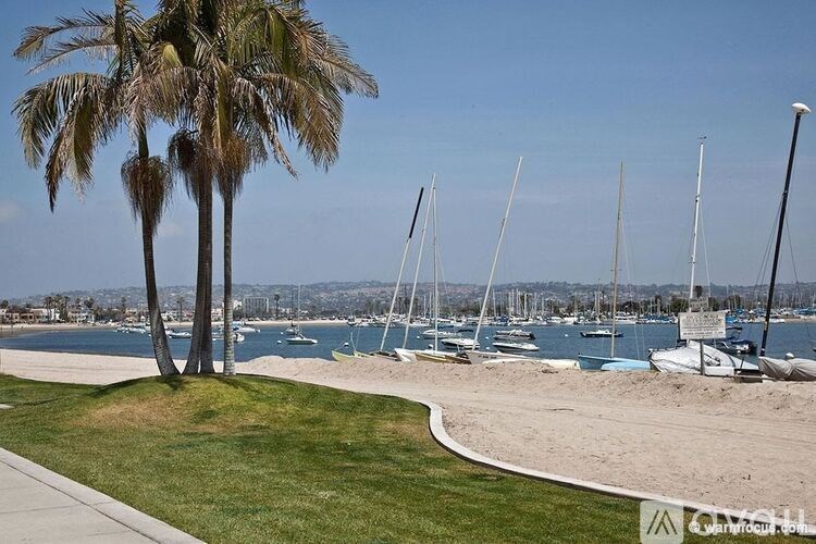 A beach with palm trees and boats in the background.