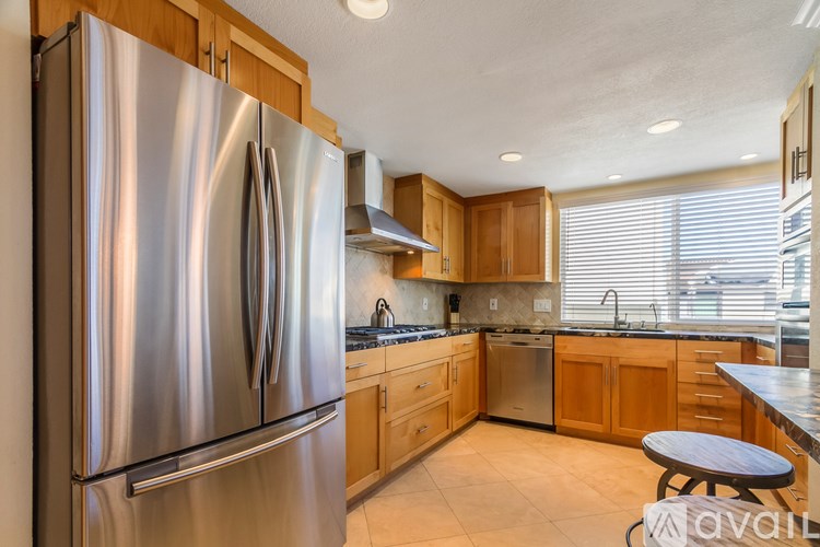 A modern kitchen with a stainless steel refrigerator and wooden cabinets.