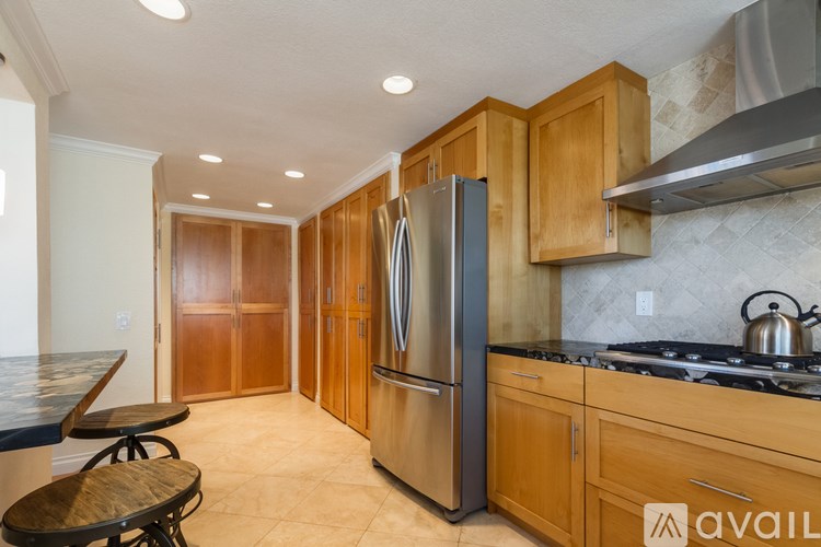 A kitchen with wooden cabinets and a stainless steel refrigerator.