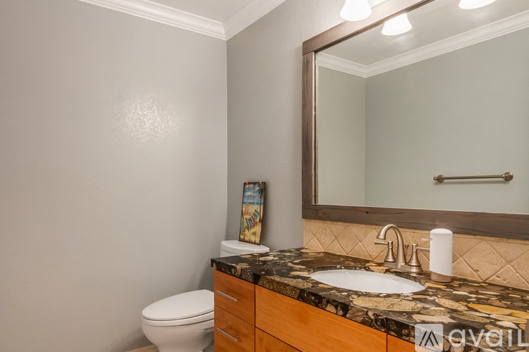 A bathroom with a toilet, sink, and mirror.