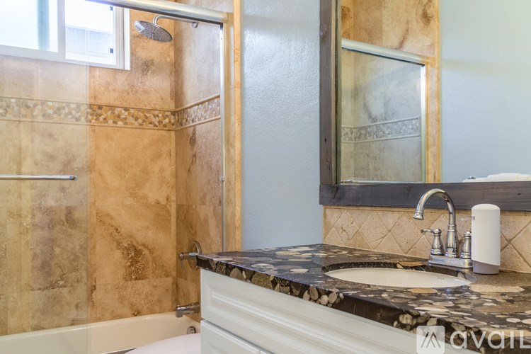 A bathroom with a marble countertop and a shower with a glass door.
