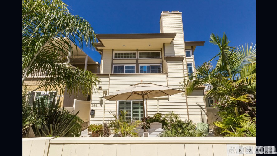 A house with a white exterior and a balcony with a table and chairs.