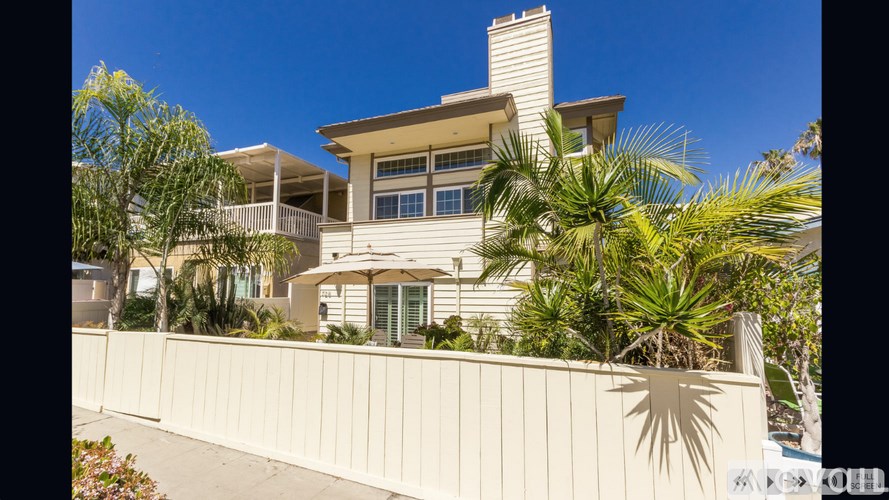 A house with a white fence and palm trees in front.