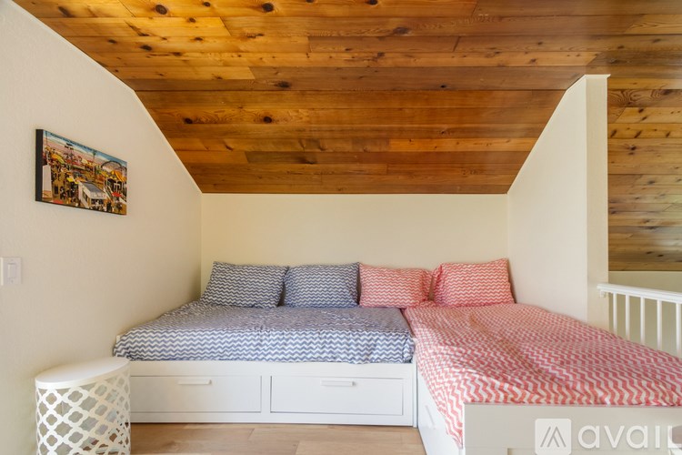 A bedroom with a wooden ceiling and two beds.