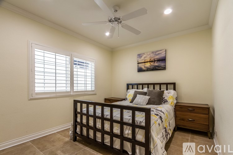 A bedroom with a bed, dresser, and a ceiling fan.