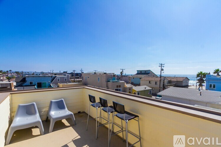 A balcony with two chairs and a table is overlooking a residential area.