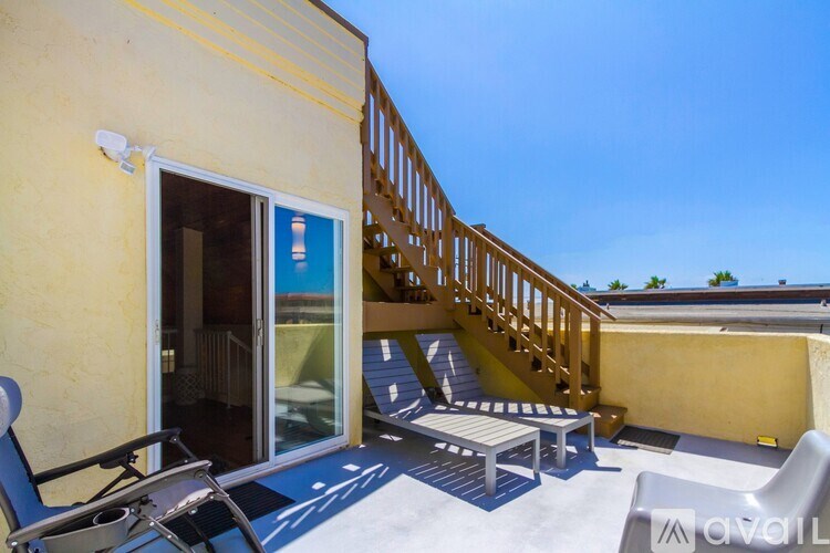 A patio with a table, chairs, and a staircase leading to a balcony.