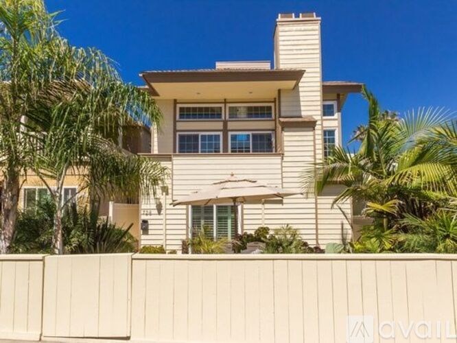 A house with a white fence and palm trees in front.