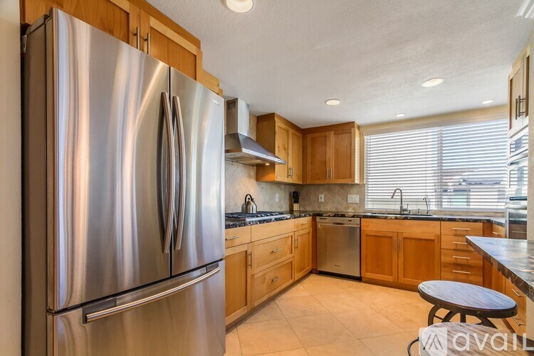 A modern kitchen with a stainless steel refrigerator and wooden cabinets.