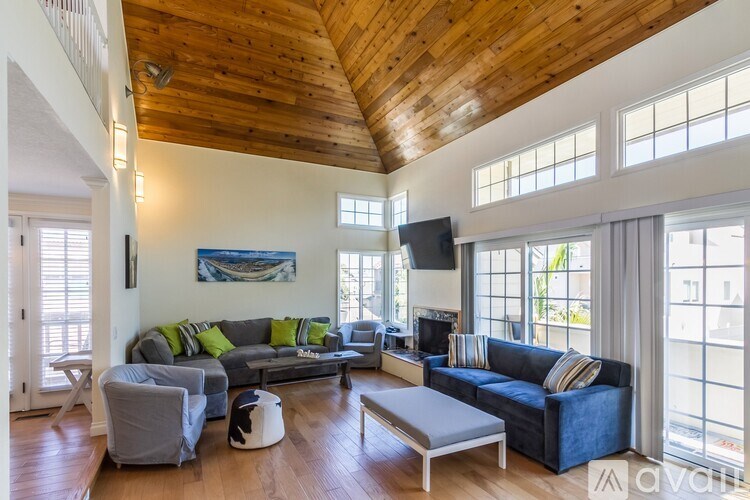 A living room with a blue couch and a wooden ceiling.